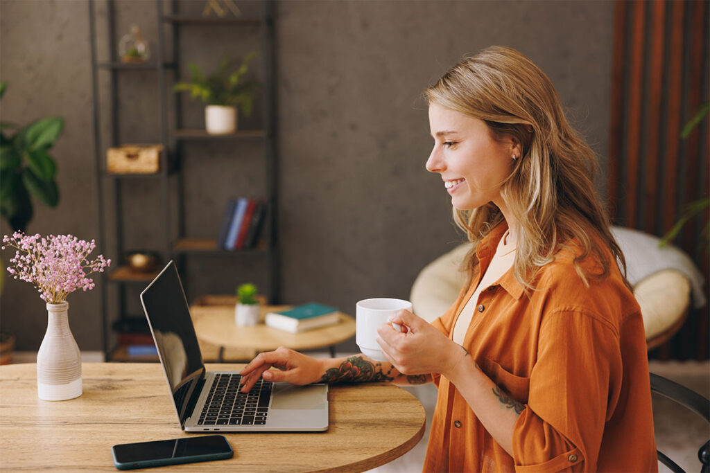 Young woman viewing financial documents indoor while drinking coffee