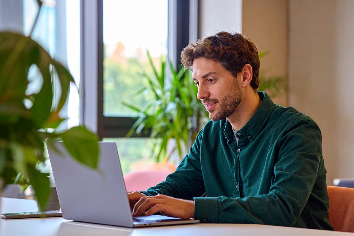 Man reporting lost card on his laptop surrounded by house plants