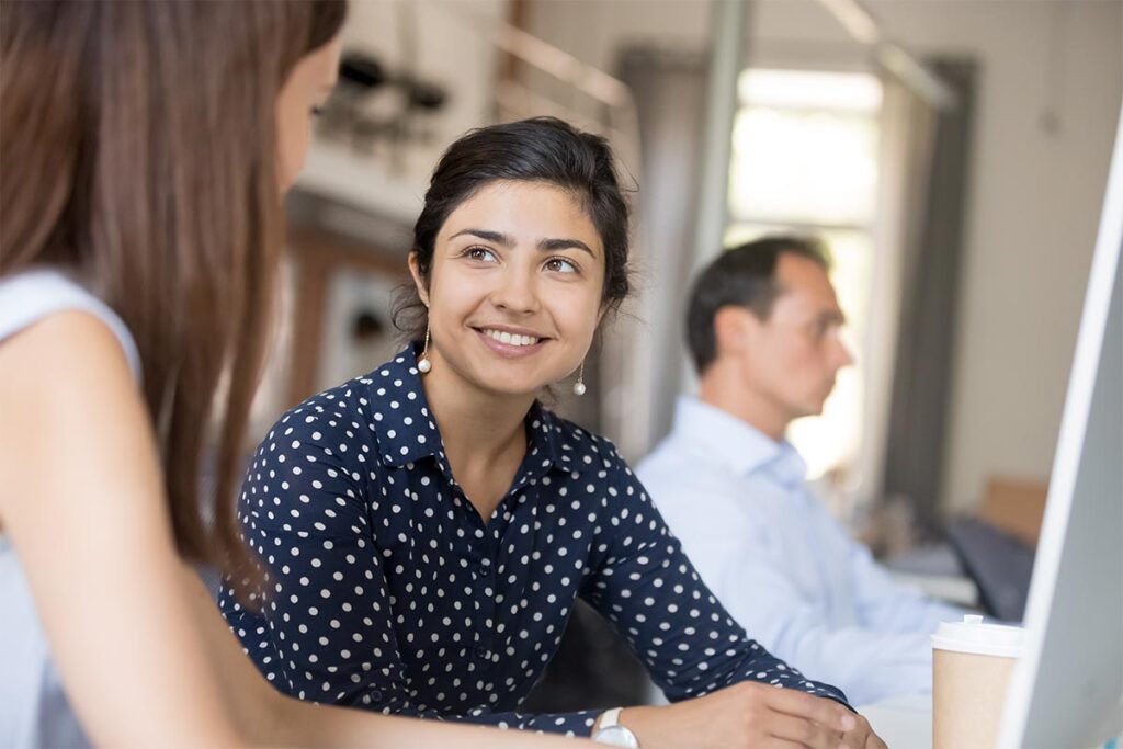 Group of employees talking with one of them in the background out of focus.
