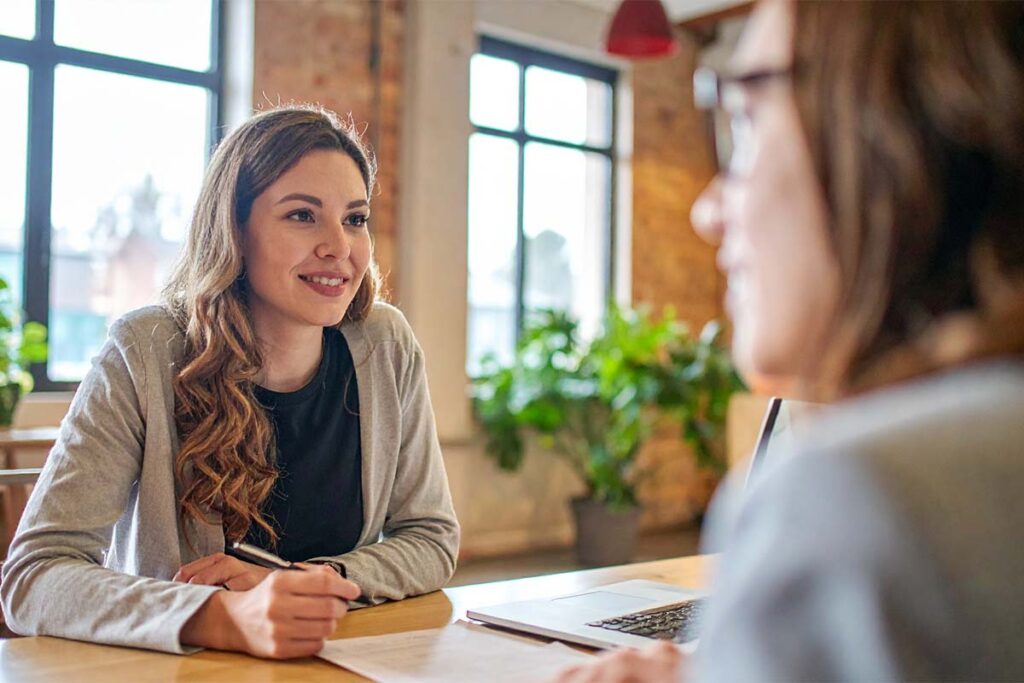 Two woman in a meeting with one in the foreground out of focus.